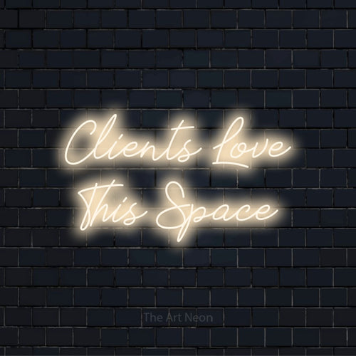 "Clients Love This Space" LED neon sign on a black brick wall