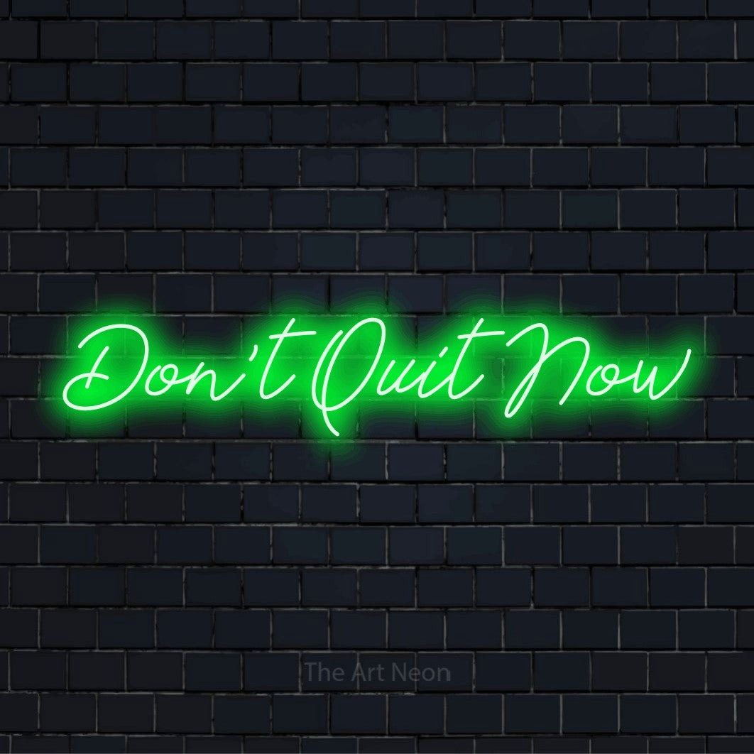 "Don’t Quit Now" text design with neon effect on a black brick wall