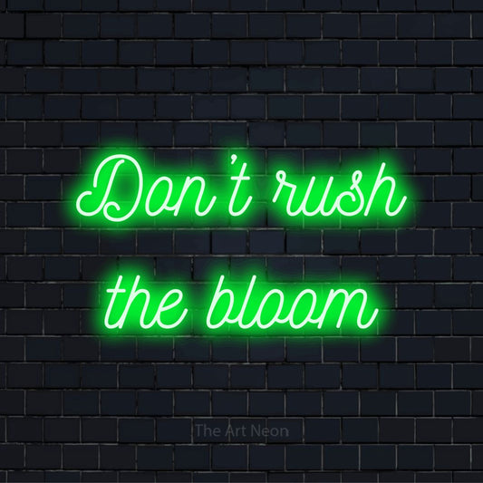 "Don’t Rush The Bloom" LED neon sign on a black brick wall
