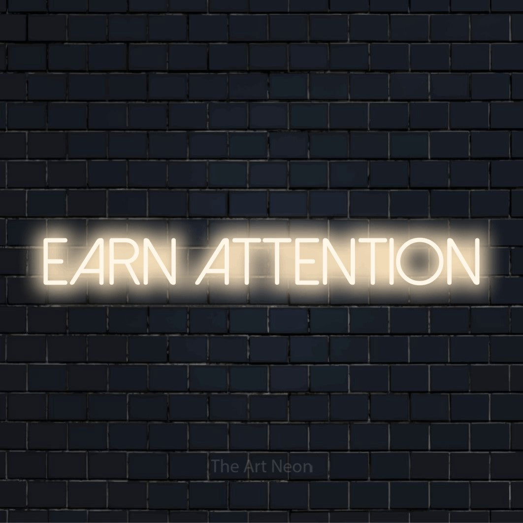 "Earn Attention" neon text design on a black brick wall