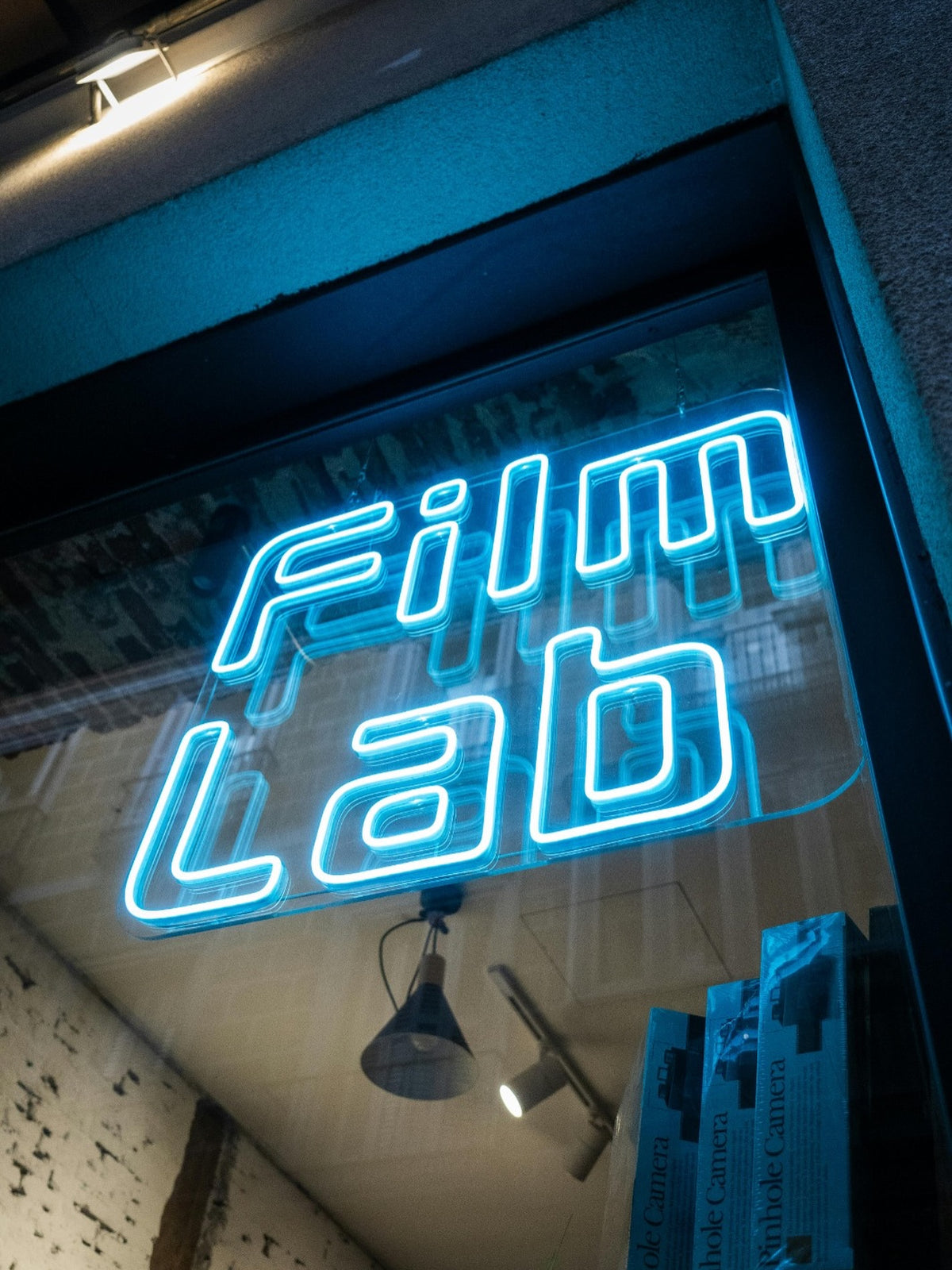 Sininen Film Lab -LED-neonlogo asennettuna kadulle avautuvan myymäläikkunan sisäpuolelle