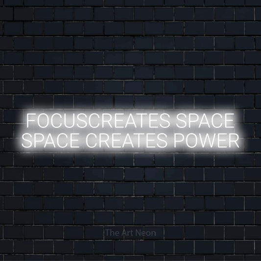 "Focus Creates Space Space Creates Power" neon text design on a black brick wall