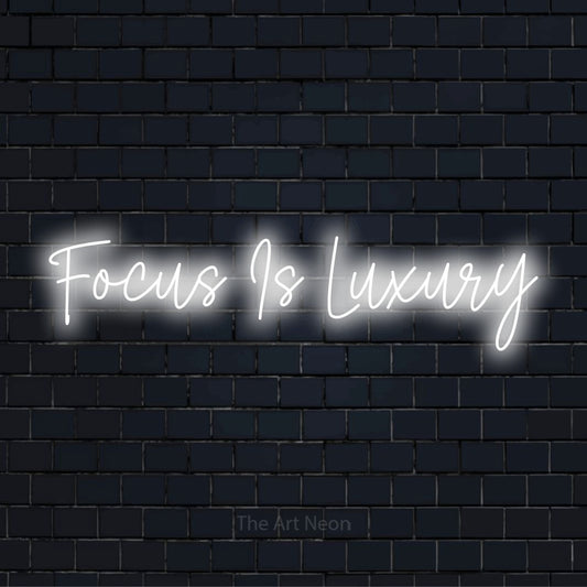"Focus Is Luxury" LED neon sign on a black brick wall
