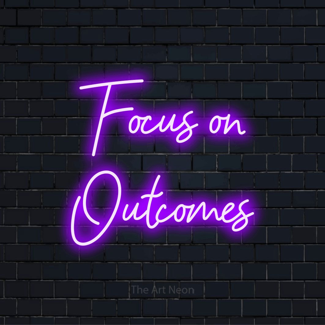 "Focus On Outcomes" glowing LED neon sign on a black brick wall