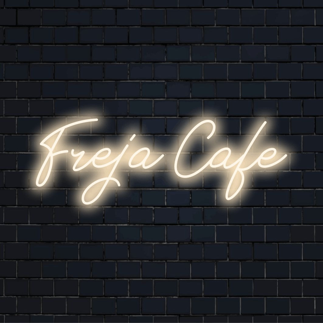 Freja Cafe Custom Name Neon Sign, bright neon lettering on dark brick wall