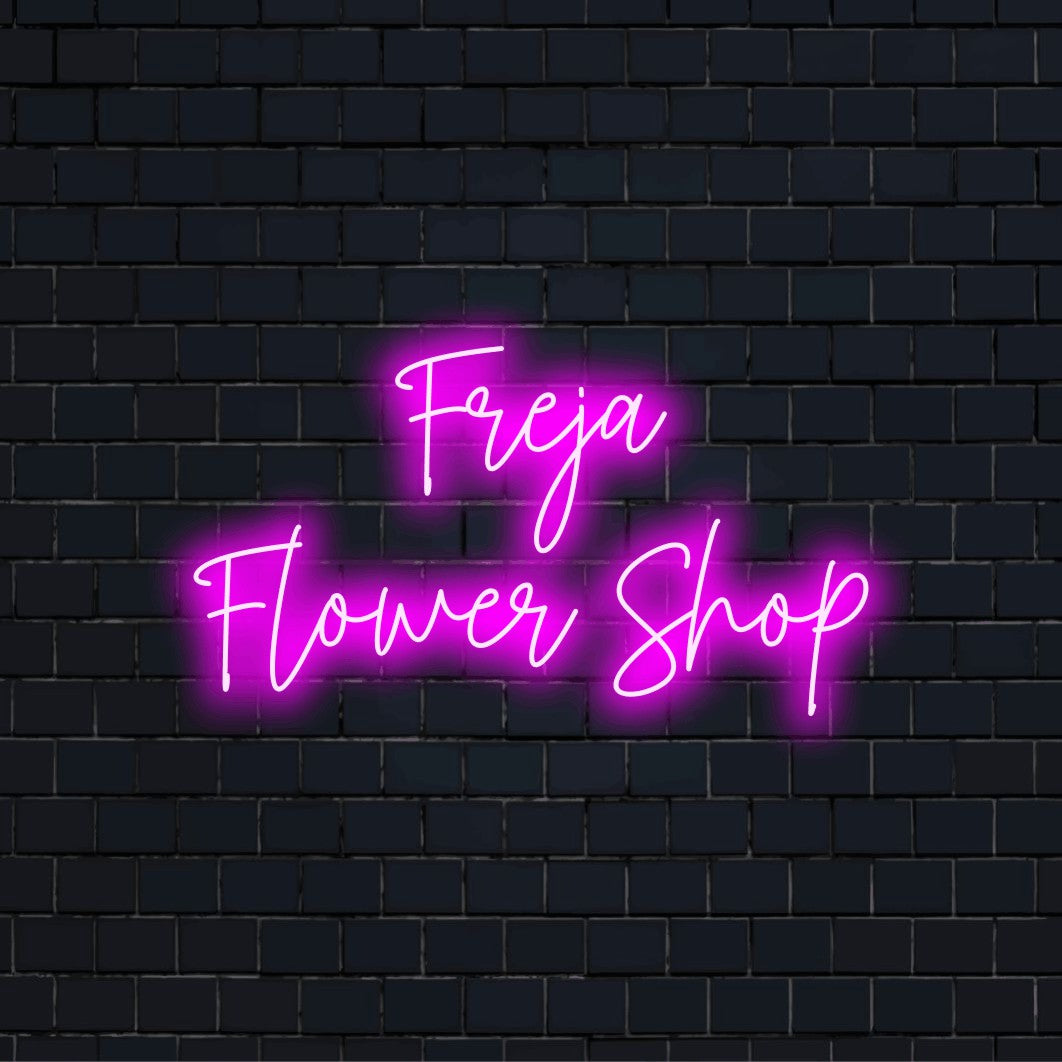 Freja Flower Shop Personalized LED Neon Sign, glowing lettering on dark brick background