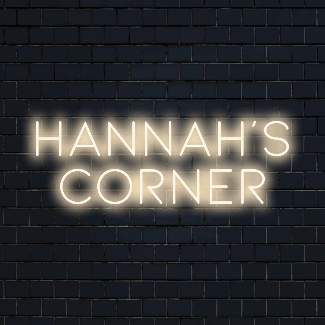 Hannah_s Corner Personalized Neon Light with bright neon glow against black brick wall