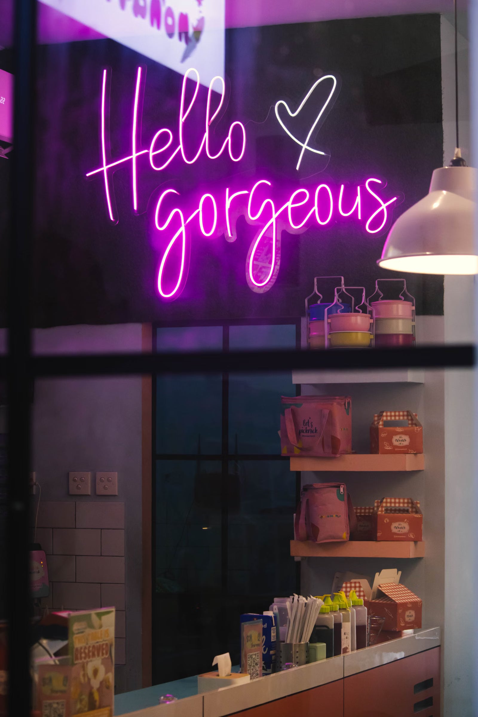 Vaaleanpunainen Hello Gorgeous -LED-neonkyltti myymälän näyteikkunan takana
