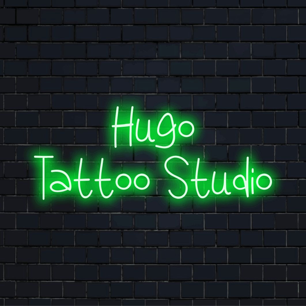 Hugo Tattoo Studio Custom Name Neon Sign, bright neon glow against brick backdrop