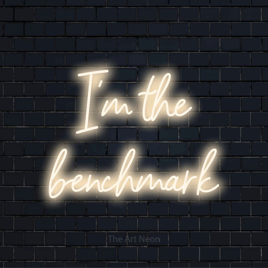 "I’m The Benchmark" neon text design on a black brick wall