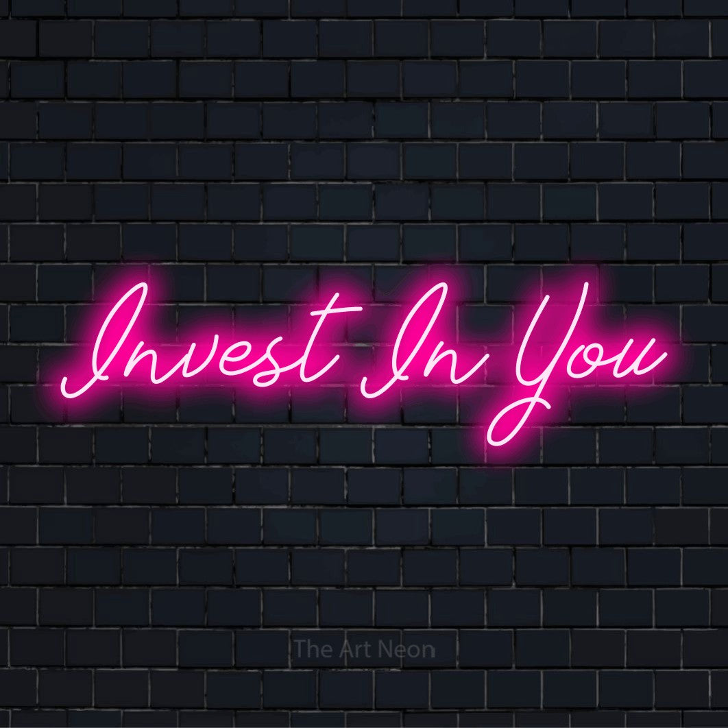 "Invest In You" glowing LED neon sign on a black brick wall