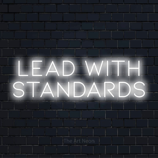 "Lead With Standards" glowing LED neon sign on a black brick wall