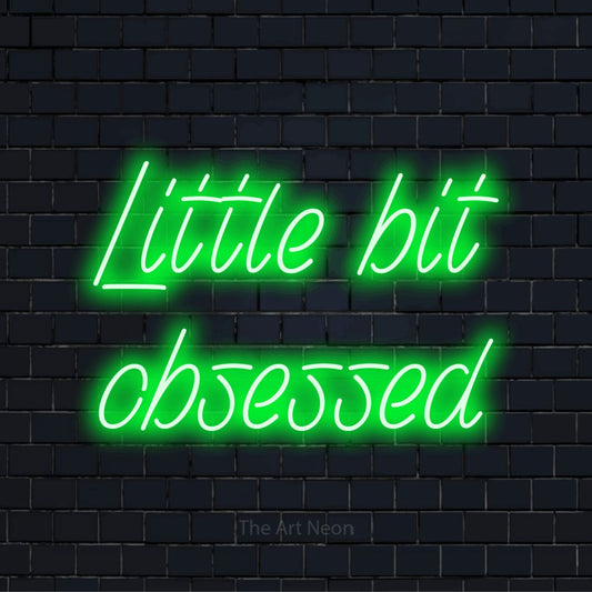 "Little Bit Obsessed" script-style LED neon sign on a black brick wall