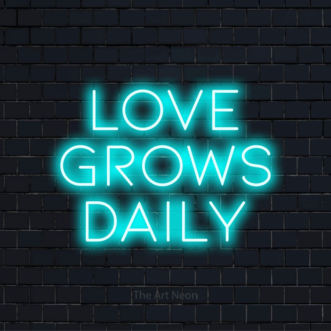 "Love Grows Daily" LED neon sign on a black brick wall