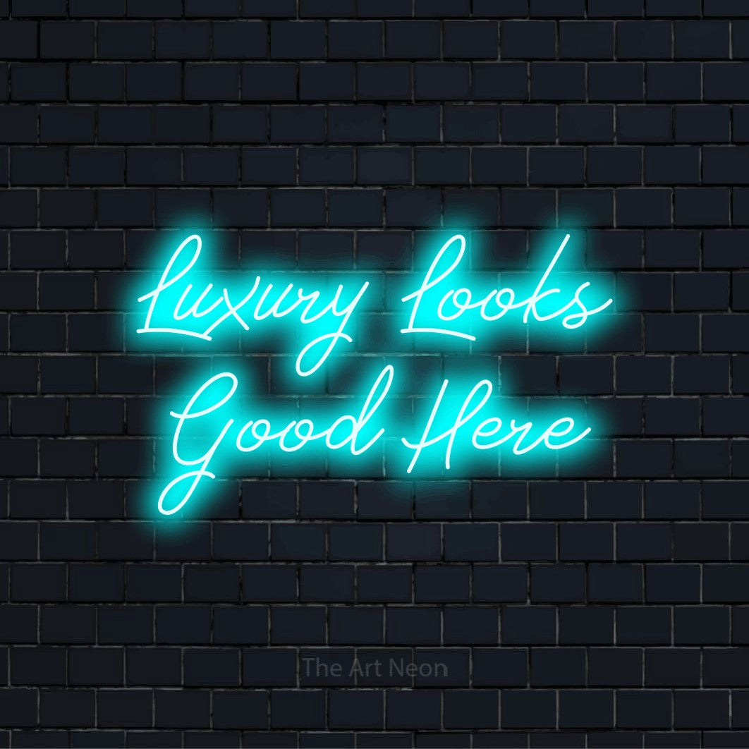 "Luxury Looks Good Here" script-style LED neon sign on a black brick wall