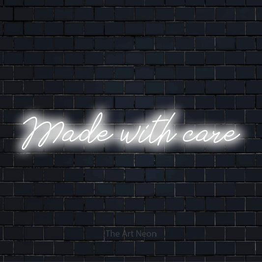 "Made With Care" script-style LED neon sign on a black brick wall