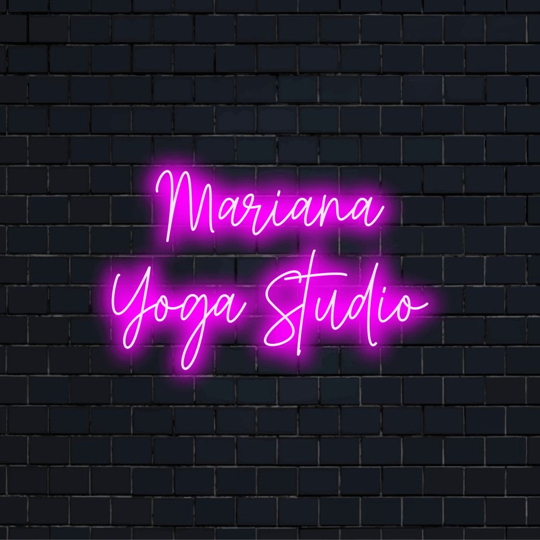 Mariana Yoga Studio Custom Name Neon Sign, bright neon glow against black brick wall