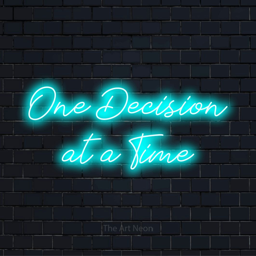 "One Decision At A Time" LED neon sign on a black brick wall
