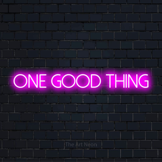 "One Good Thing" glowing LED neon sign on a black brick wall