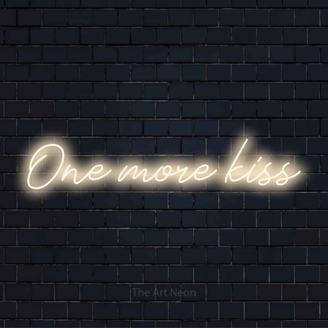 "One More Kiss" neon text design on a black brick wall
