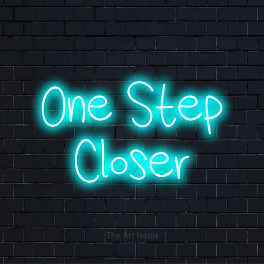 "One Step Closer" LED neon sign on a black brick wall