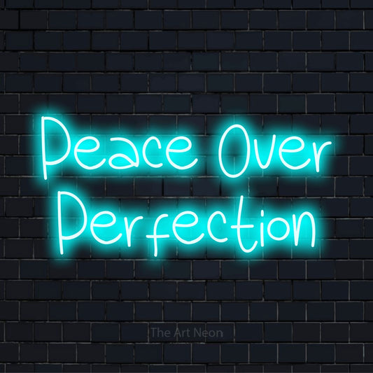 "Peace Over Perfection" script-style LED neon sign on a black brick wall