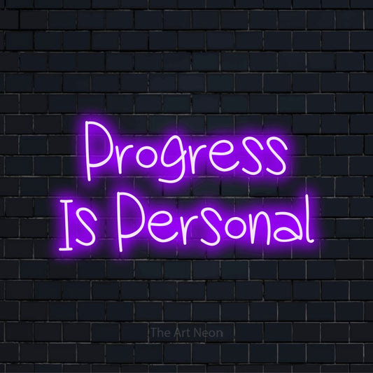 "Progress Is Personal" script-style LED neon sign on a black brick wall