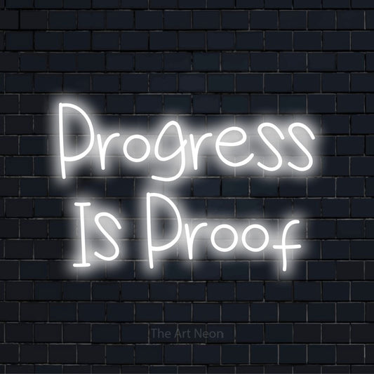 "Progress Is Proof" glowing LED neon sign on a black brick wall