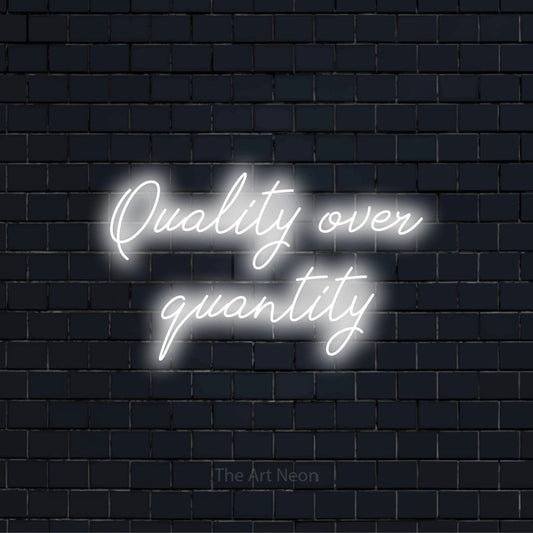 "Quality Over Quantity" neon text design on a black brick wall