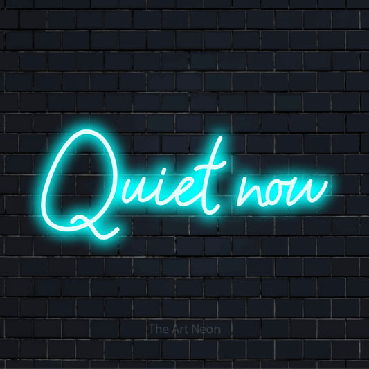 "Quiet Now" glowing LED neon sign on a black brick wall