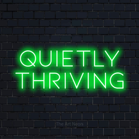"Quietly Thriving" LED neon sign on a black brick wall