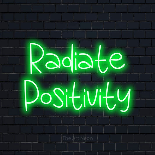 "Radiate Positivity" text design with neon effect on a black brick wall