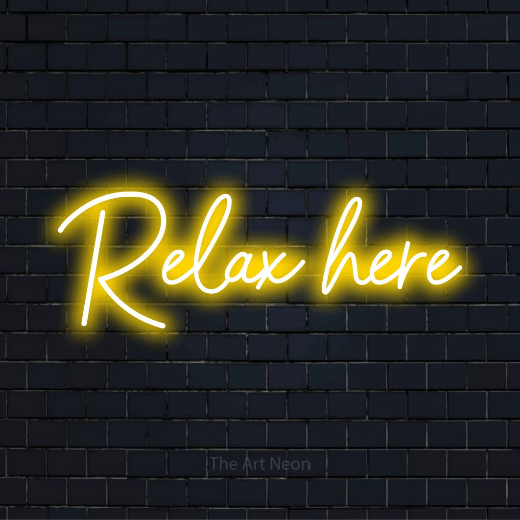 "Relax Here" script-style LED neon sign on a black brick wall