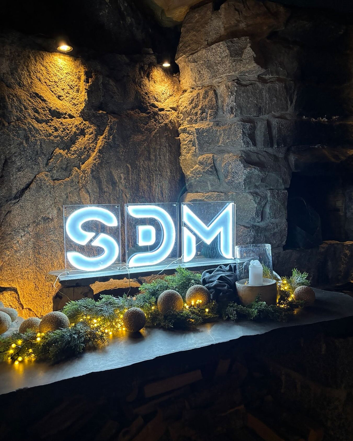 Yksilöllinen SDM-logo LED-neonkylttinä kiviseinällä