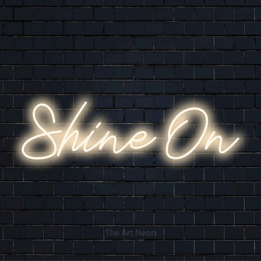 "Shine On" glowing LED neon sign on a black brick wall