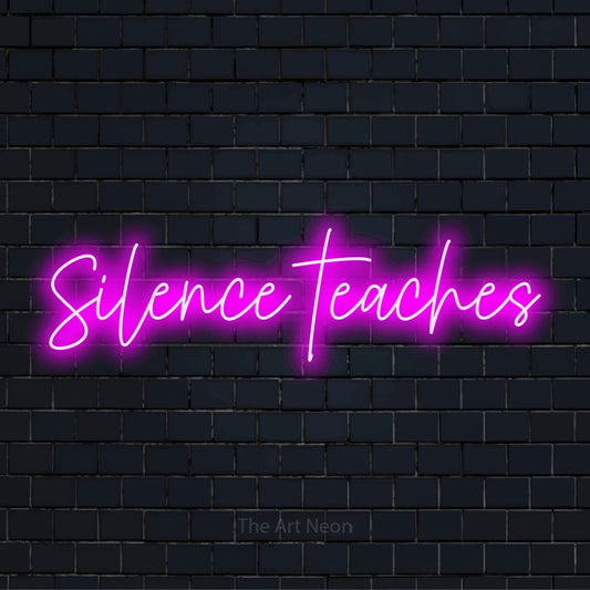 "Silence Teaches" LED neon sign on a black brick wall