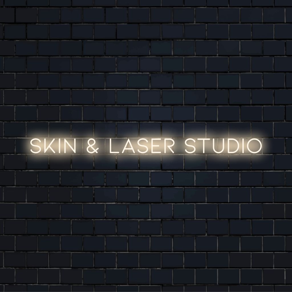 Skin Laser Studio Neon Sign, glowing wall decor against black brick wall