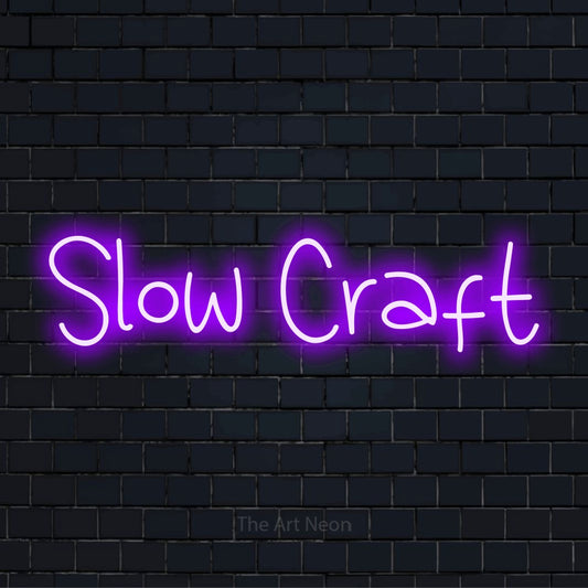 "Slow Craft" neon text design on a black brick wall