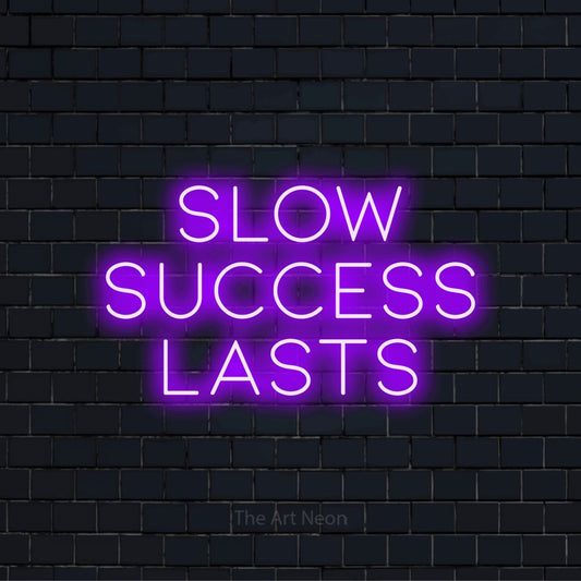 "Slow Success Lasts" LED neon sign on a black brick wall