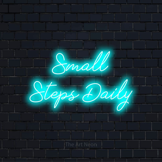"Small Steps Daily" LED neon sign on a black brick wall