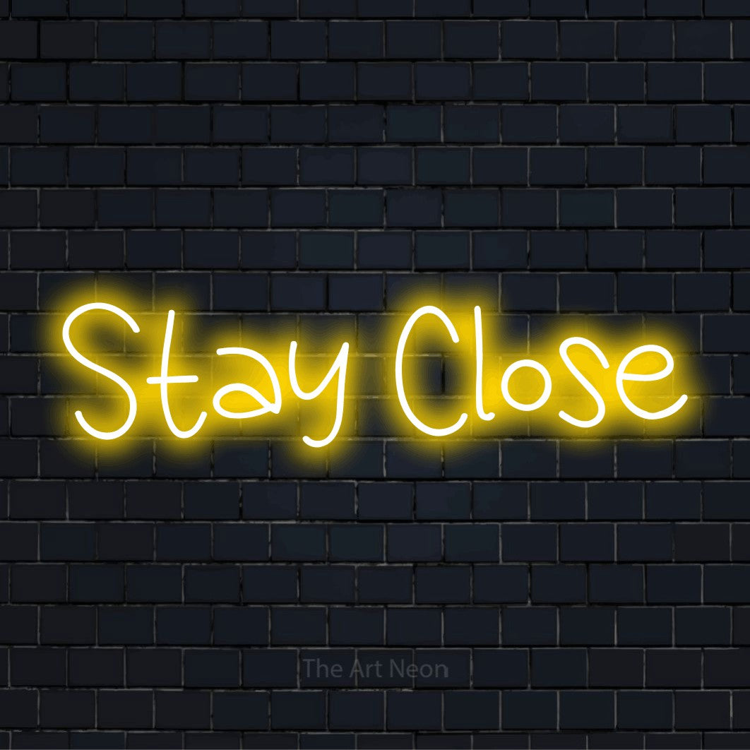 "Stay Close" glowing LED neon sign on a black brick wall