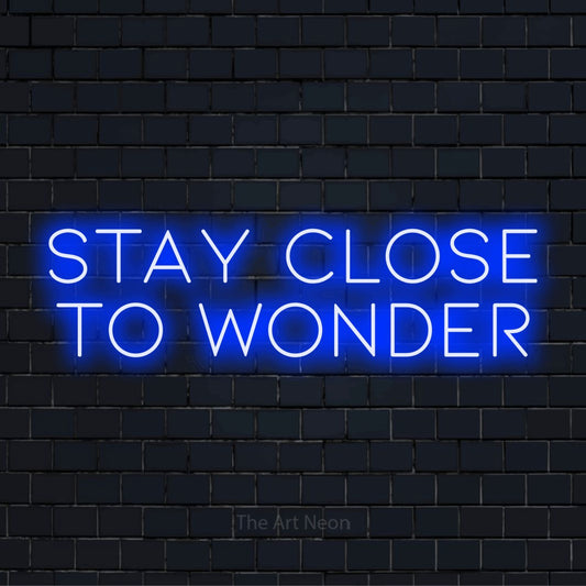 "Stay Close To Wonder" neon text design on a black brick wall