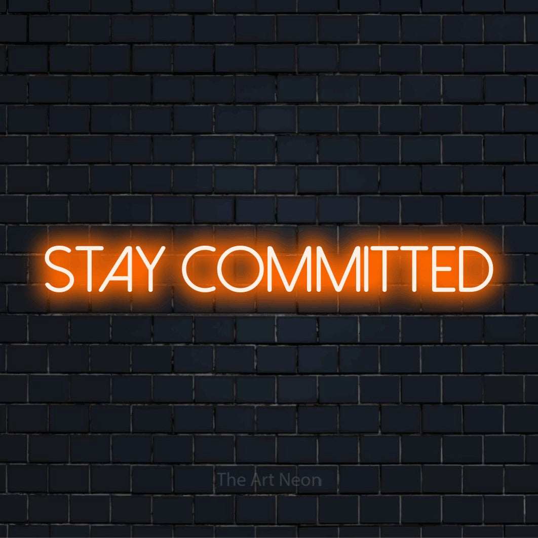 "Stay Committed" LED neon sign on a black brick wall