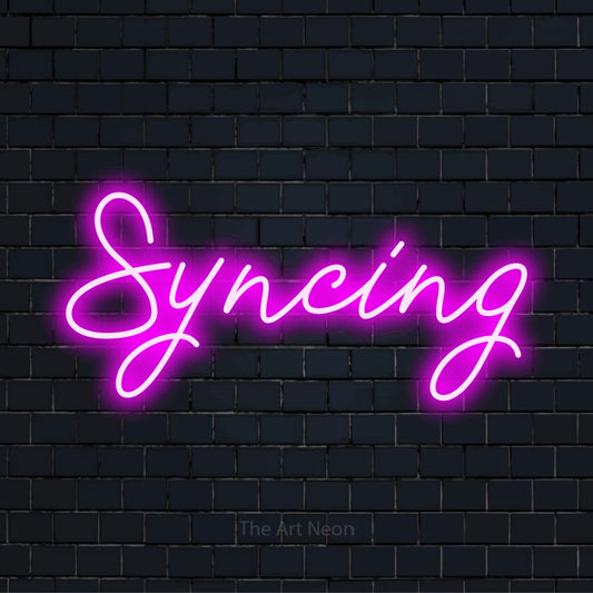 "Syncing" script-style LED neon sign on a black brick wall
