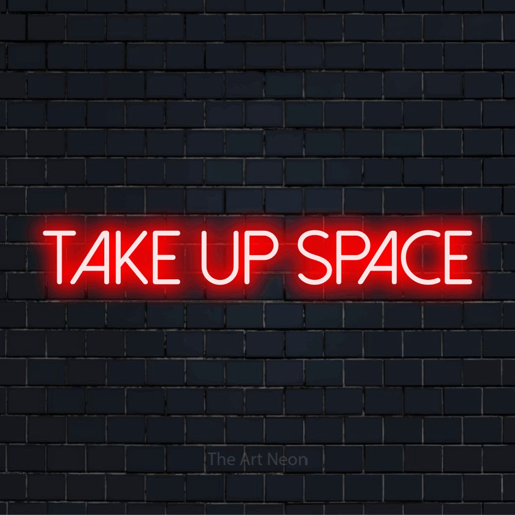 "Take Up Space" LED neon sign on a black brick wall