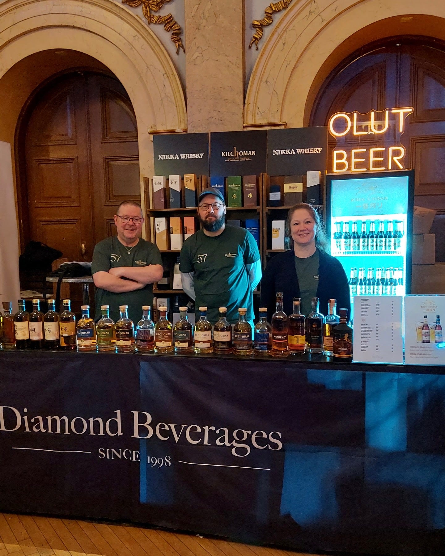 Warm OLUT BEER text LED neon above the Diamond Beverages tasting stand.