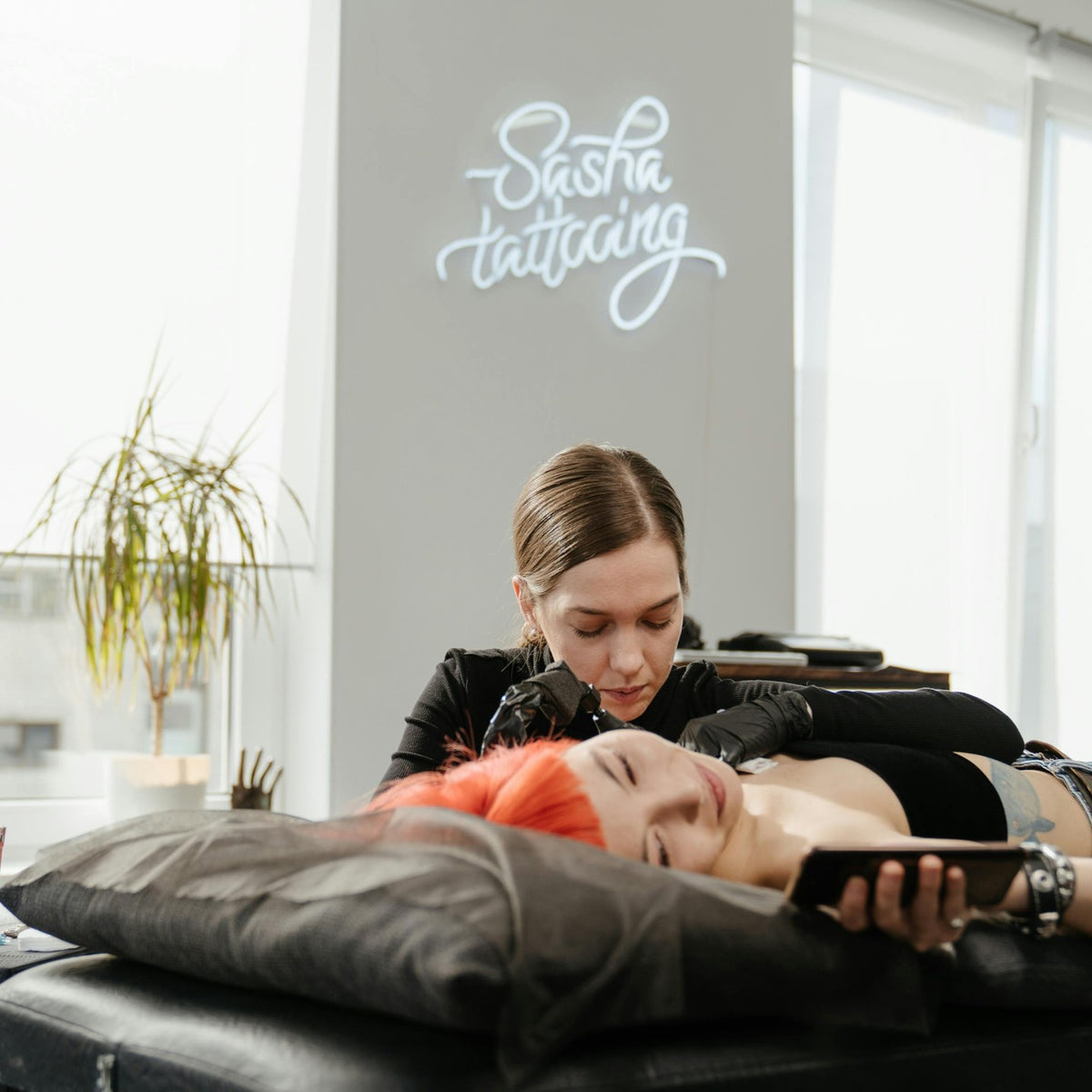 Tatuointistudioon asennettu LED-neonkyltti tatuoijan logosta