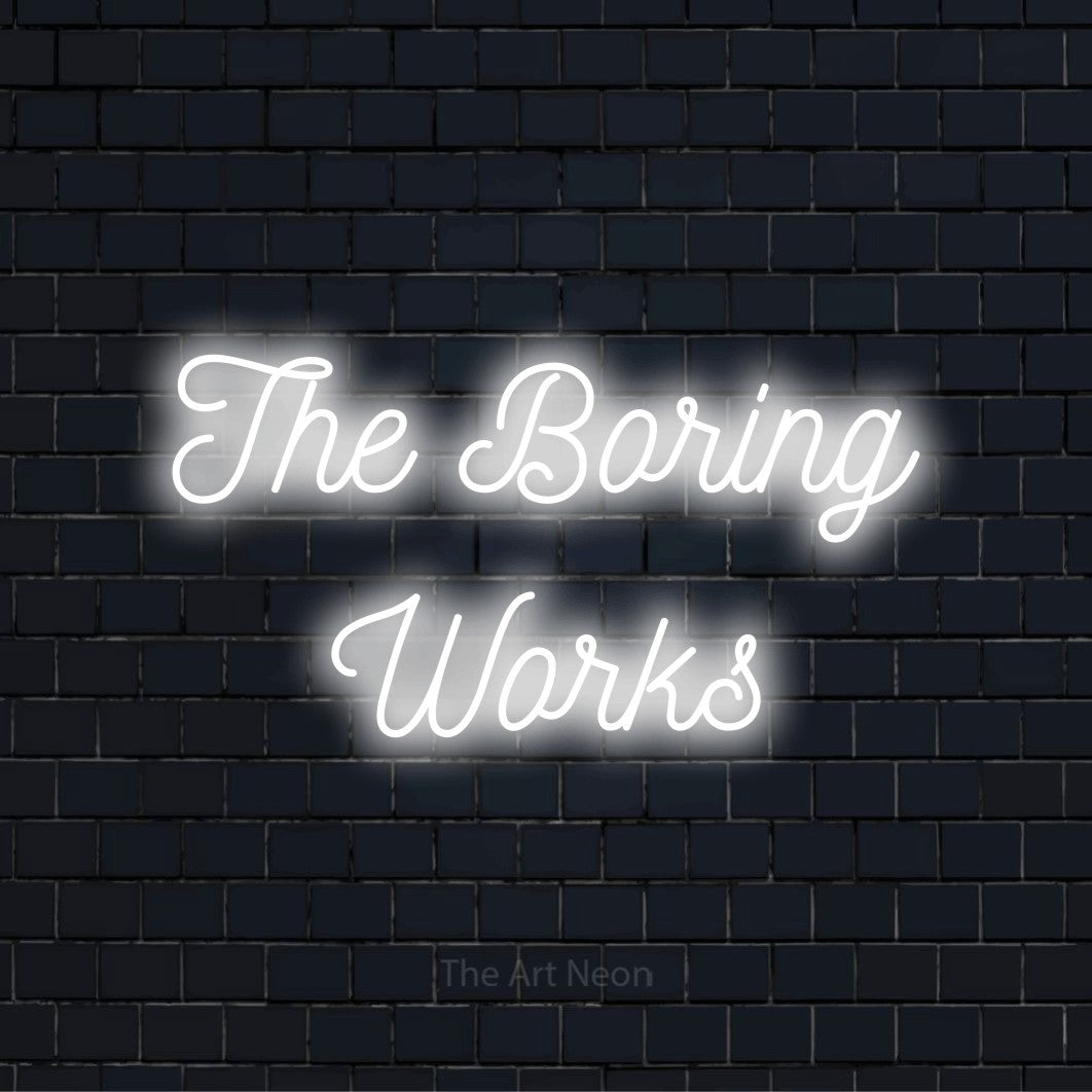 "The Boring Works" glowing LED neon sign on a black brick wall