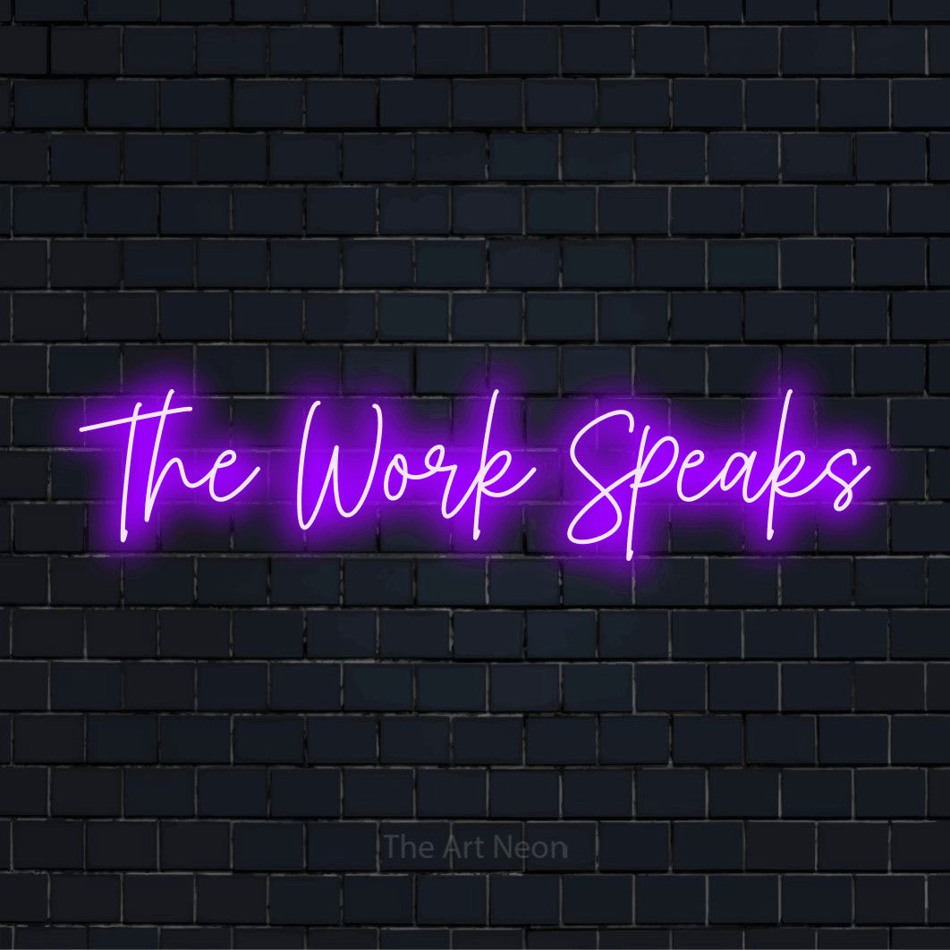 "The Work Speaks" script-style LED neon sign on a black brick wall