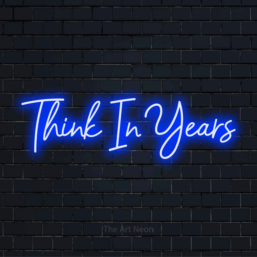 "Think In Years" LED neon sign on a black brick wall